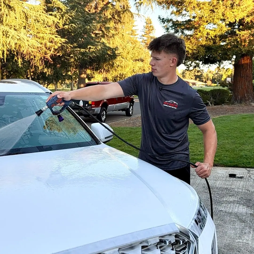 Ryan rinsing the hood of a customer's car in their driveway
