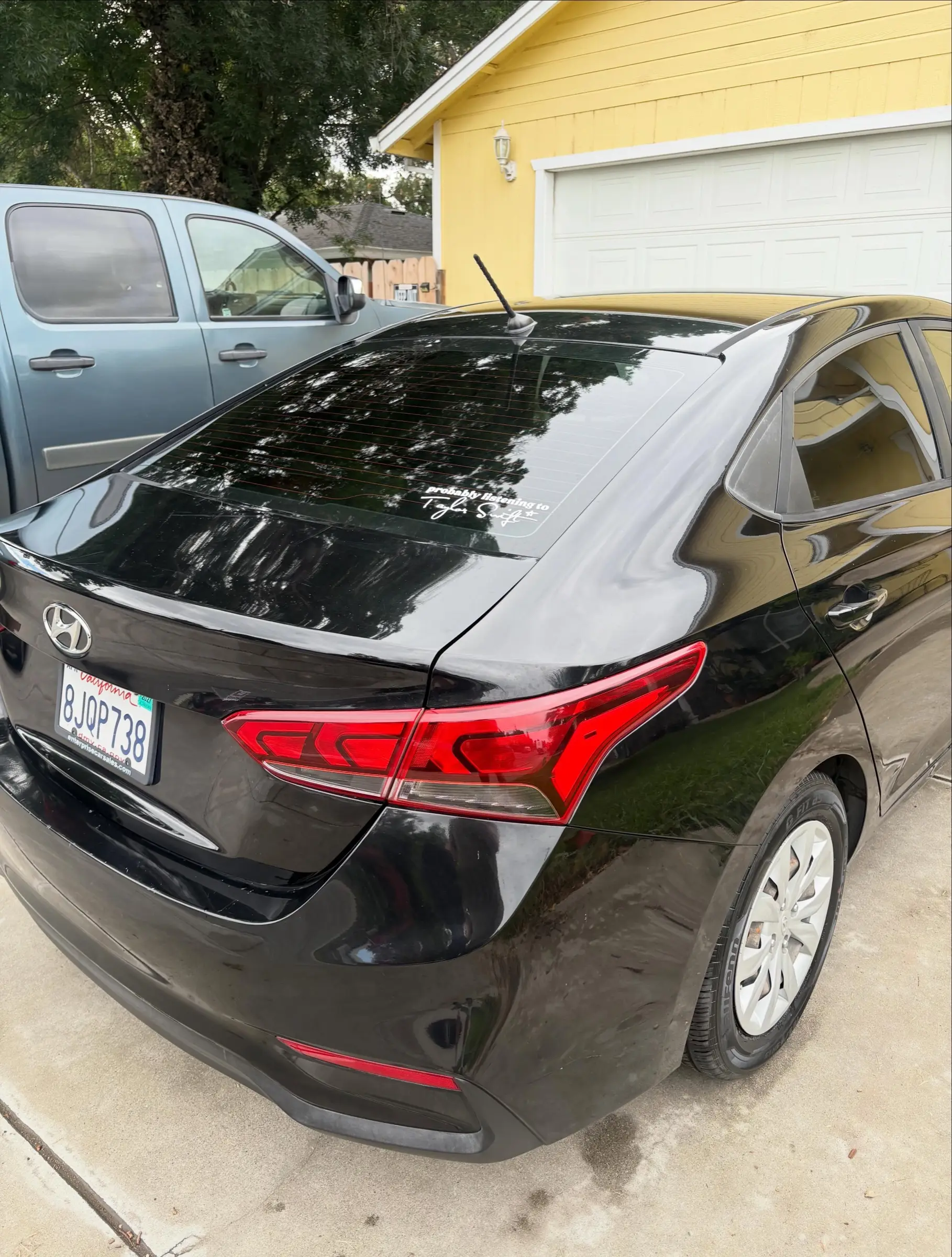 Black Hyundai Accent, rear three-quarter view, in a driveway after a detail