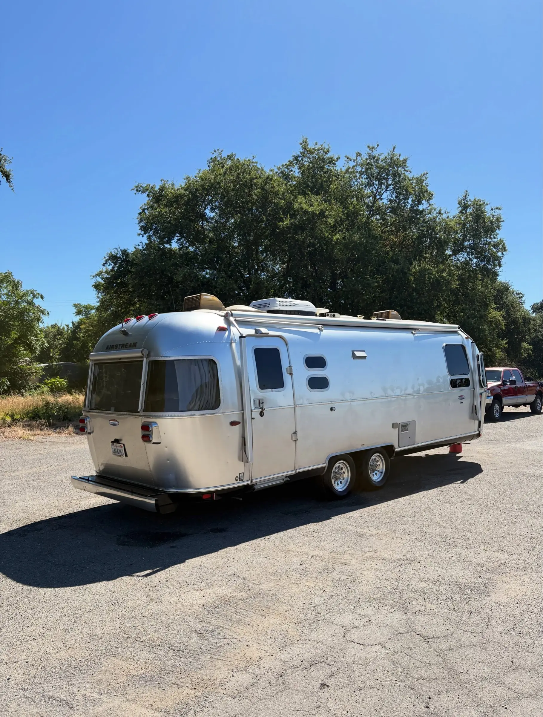 Polished Airstream travel trailer parked under trees after a detail