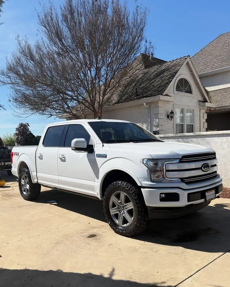 White Ford F-150 in front of a brick house after an exterior detail